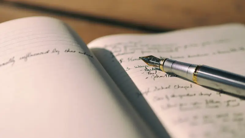 Fountain pen resting on an open journal filled with handwritten notes